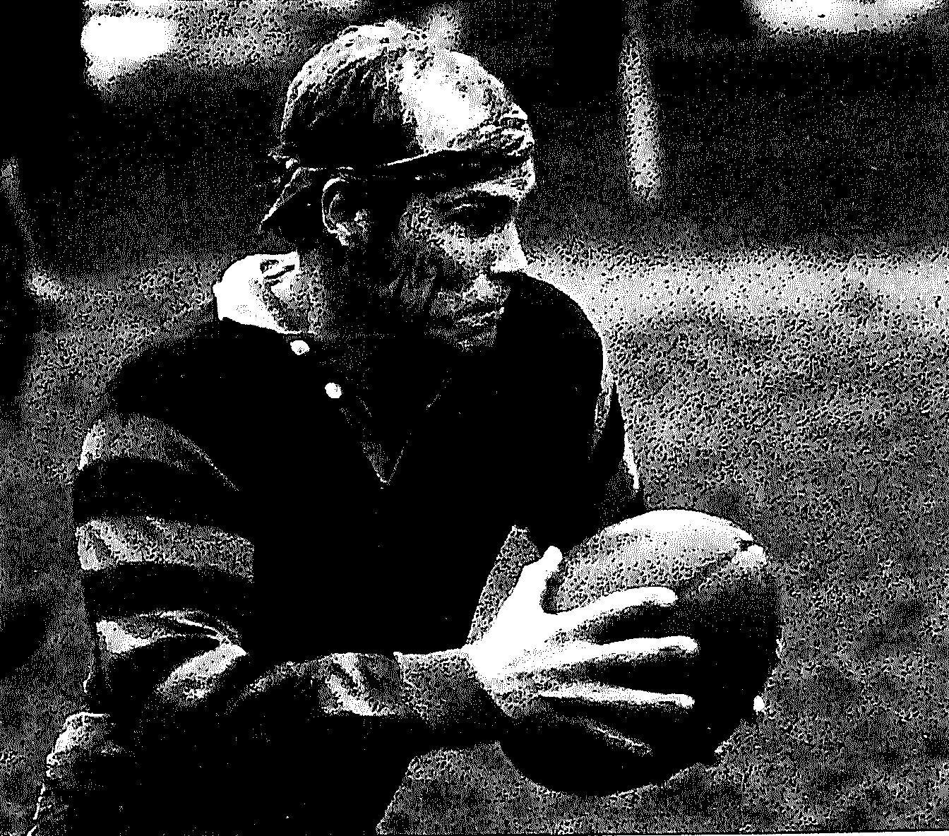 Jack Coates in a hooped jersey with a headband, muddy-faced, carrying a rugby ball in both hands