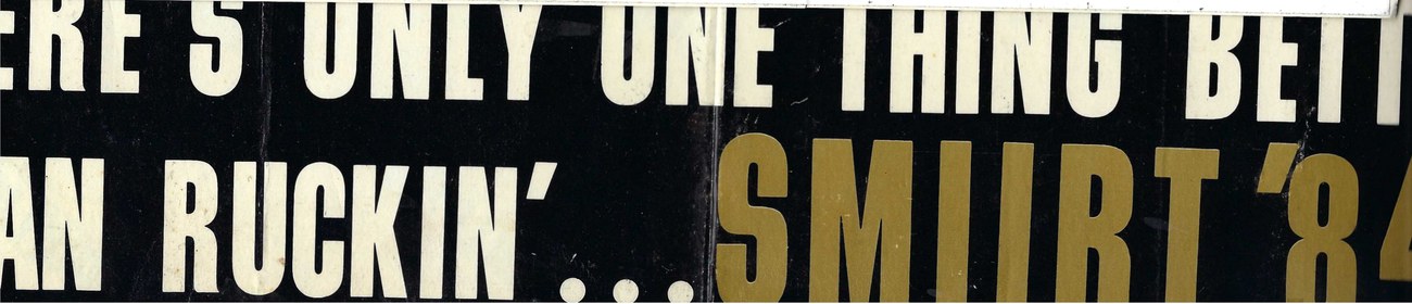 Black bumper sticker with white and gold lettering, partly obscured, reading there's only one thing better than ruckin' and SMUURT '84