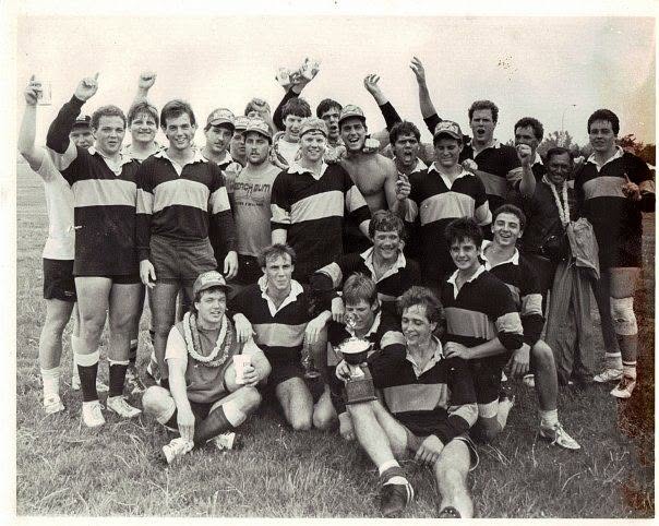Black and white photograph of the Mizzou squad with arms raised on the pitch