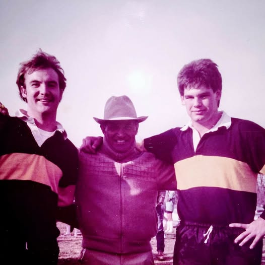 Faded color photograph of three Mizzou players in hooped jerseys with their arms around each other