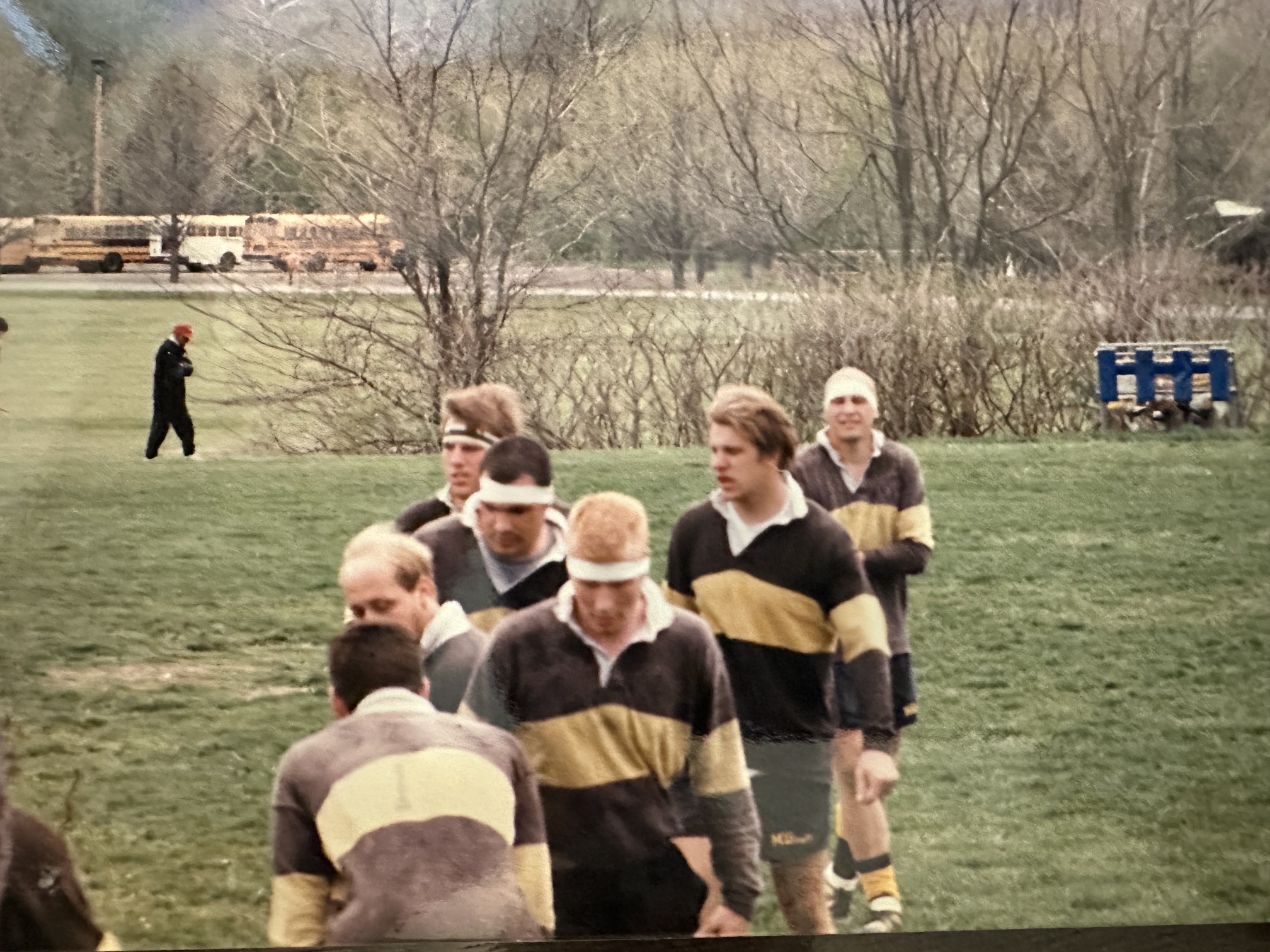 Mizzou forwards in black and gold hooped jerseys forming up for a lineout during the final match of the 1996-97 season, with school buses parked beyond the far touchline