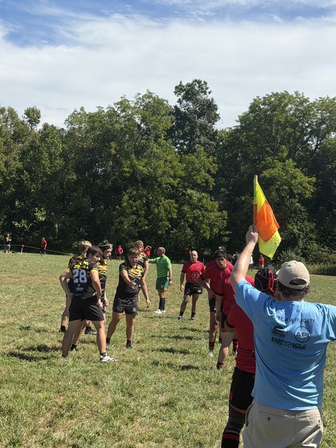 Mizzou and Drury players set up for a lineout as the touch judge raises the flag