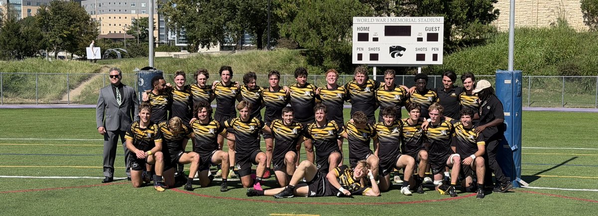 The 2026 Mizzou Rugby squad and coaches lined up for a team photo in front of the posts and the World War I Memorial Stadium scoreboard after the win at Kansas State