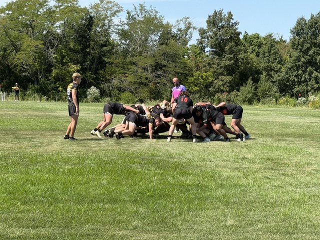 Mizzou and Oklahoma State packs bound in a scrum, referee alongside