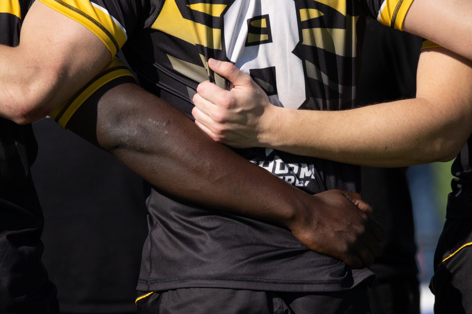 A second close view of Mizzou players gripping arms in the huddle
