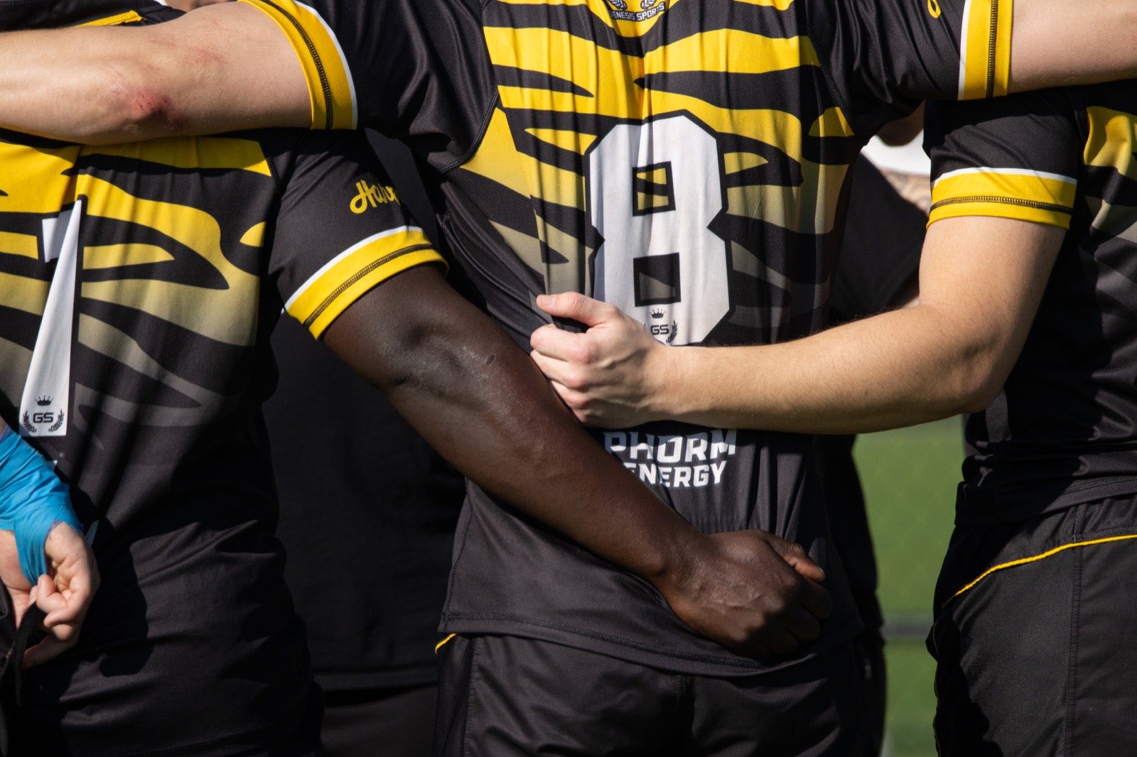Close view of Mizzou players linking arms in the huddle, one wearing number eight