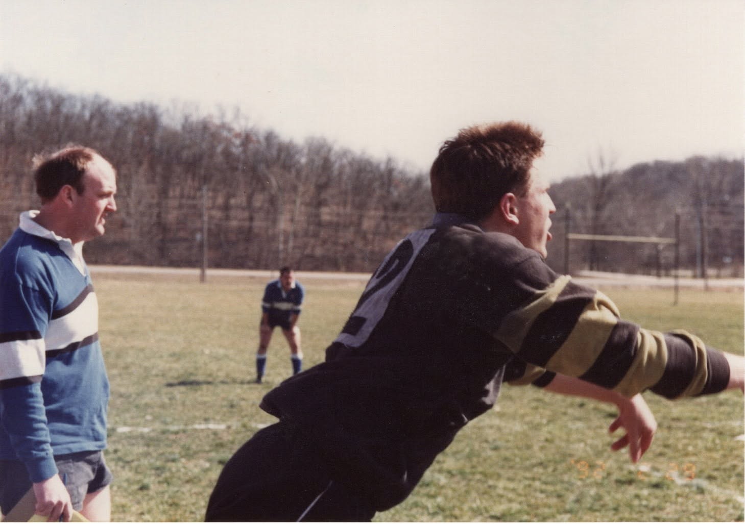 Two men talk on the touchline, one leaning toward the camera